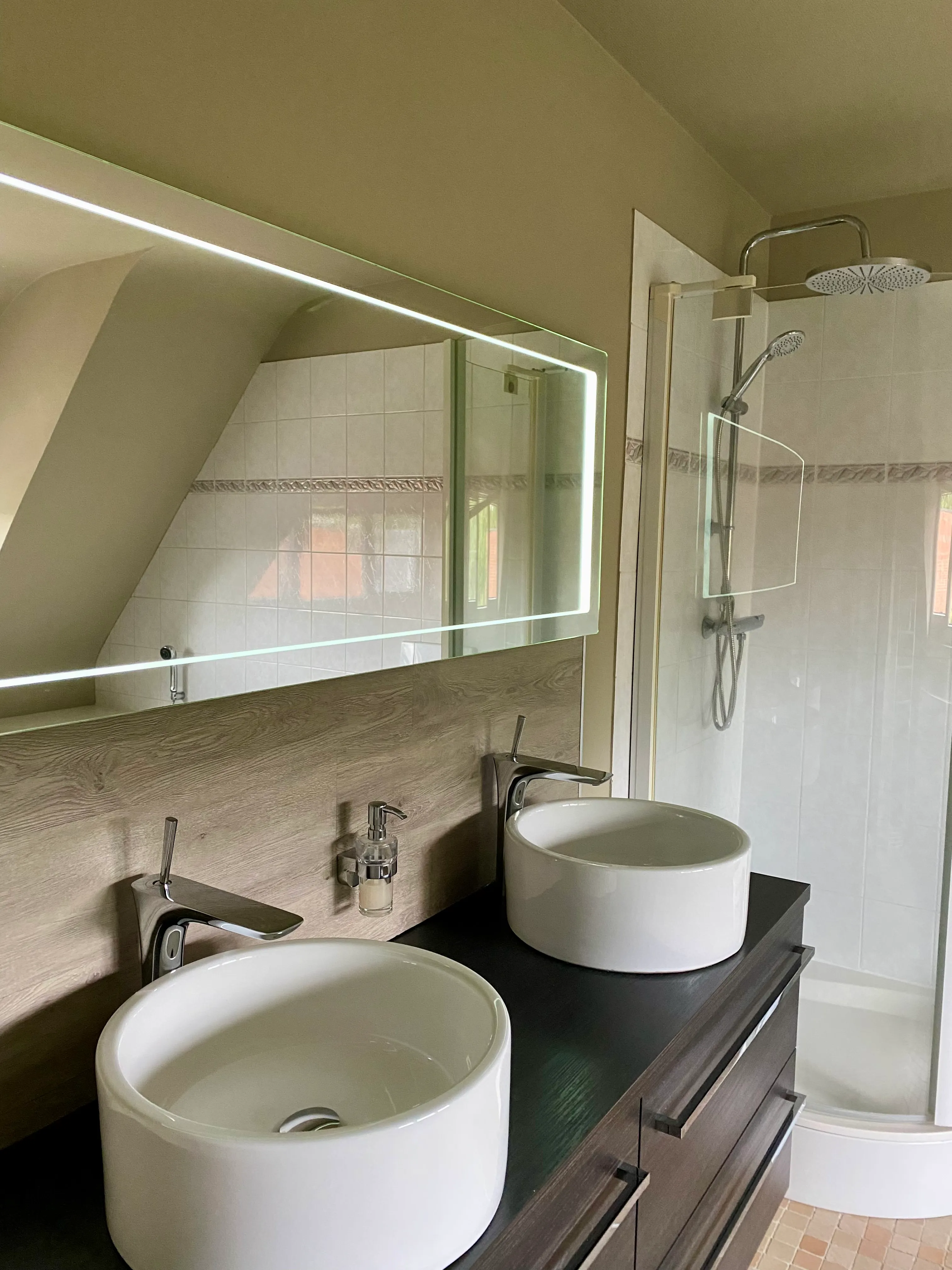 Badkamer met twee ronde wastafels, een verlichte spiegel en een douche