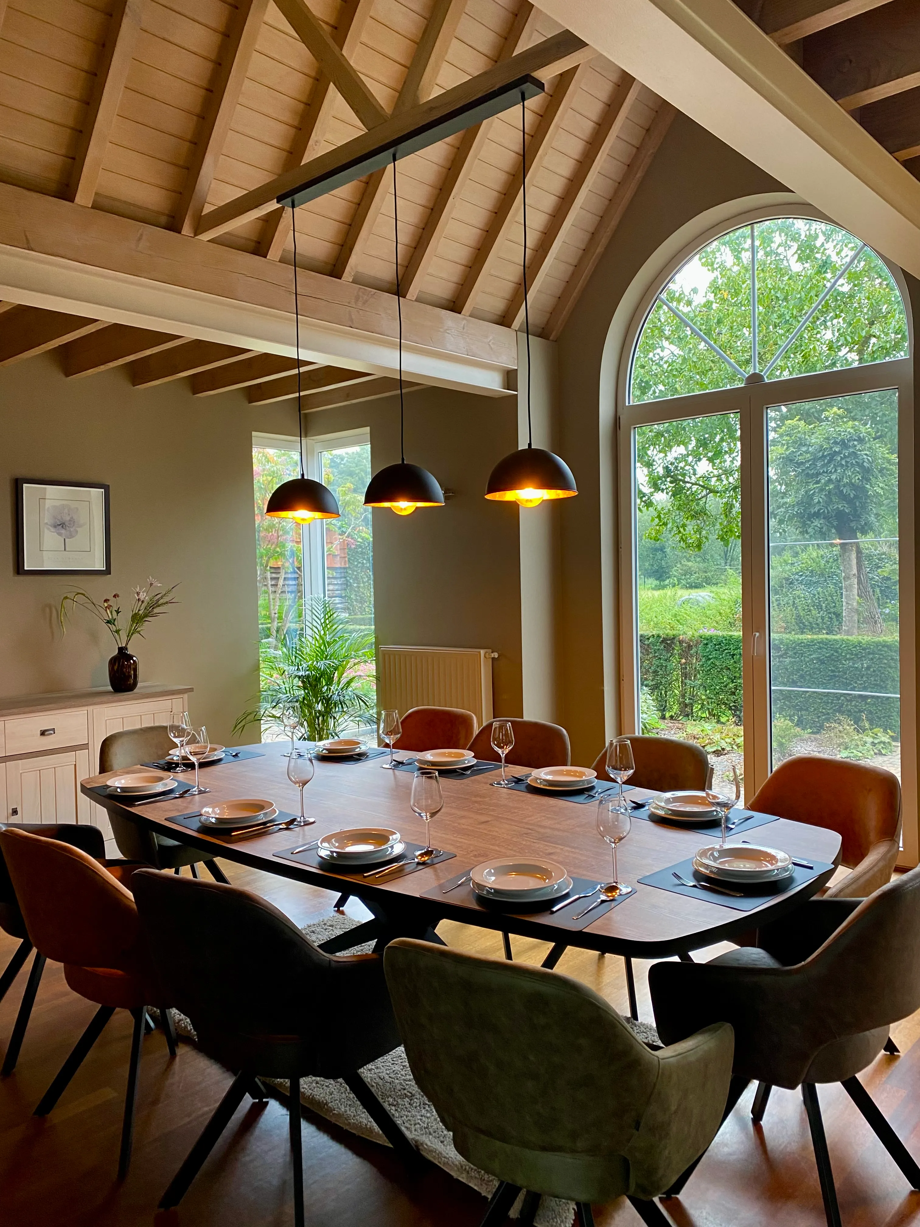 Dezelfde eetkamer van de andere kant, onder de houten dakspanten, met de tafel gedekt