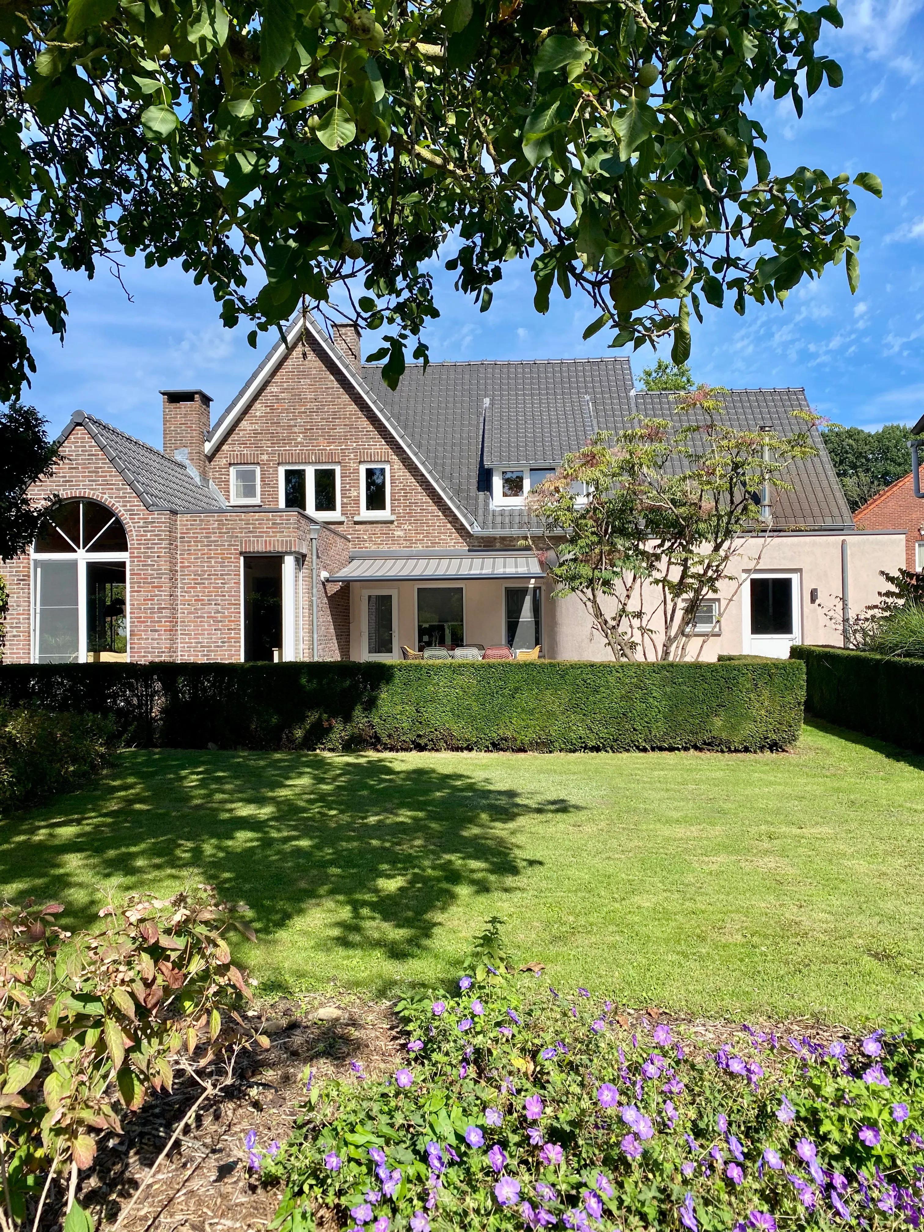 De achtergevel met terras en luifel, gezien vanuit de tuin
